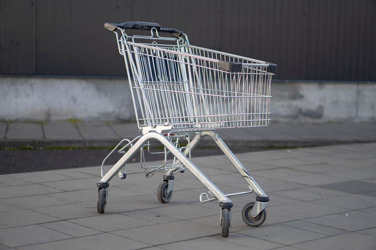 Services A solitary metal shopping cart stands in an empty outdoor parking lot, capturing the essence of consumerism.